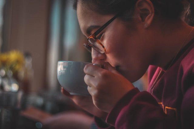 A man drinking a cup of tea from a ceramic mug